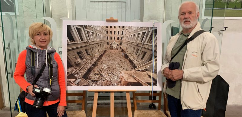 Olena Dolzhenko und Wladimir Ogloblin vor einem Bild ihrer zerstörten Fotoschule in der ukrainischen Stadt Charkiw
